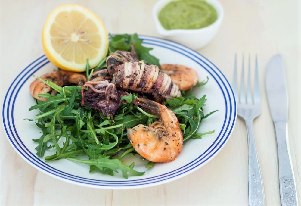 Grilled calamari and king prawns served with rocket and lemon &mdash; a Mediterranean dish seasoned with oregano and herbs.